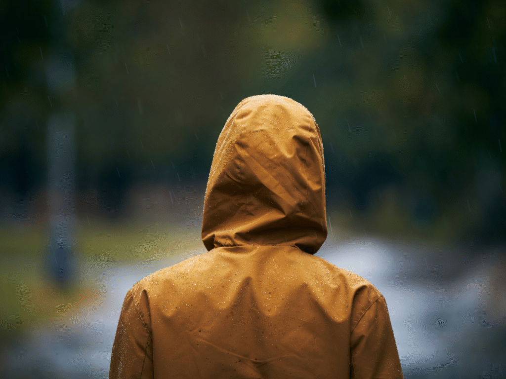 Yellow Raincoat in the Rain Man with his back to the camera wearing a yellow raincoat with with hood. up