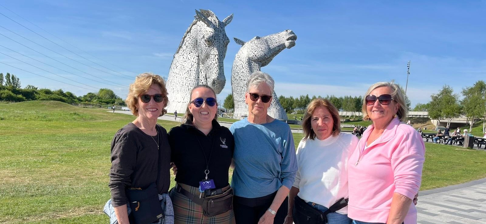 Lesley with tour guests smiling in front of the Kelpies horse sculptures
