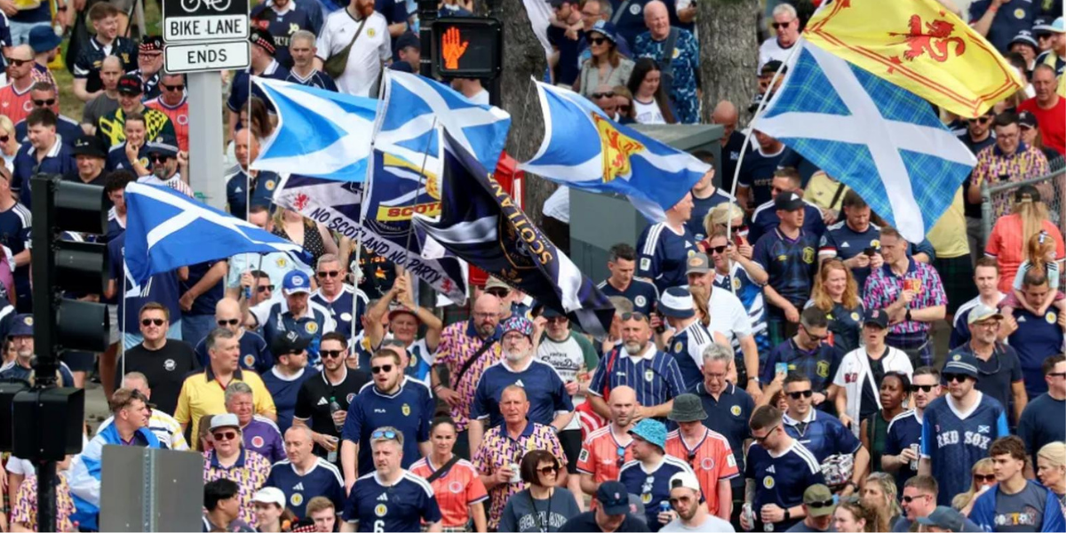 Tartan Army fans marching with Scotland flags through city streets