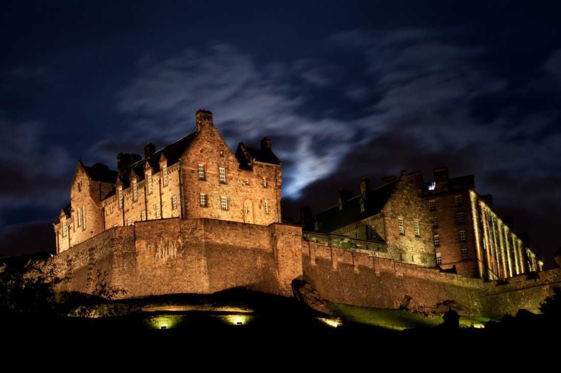 Edinburgh Castle illuminated at night under a moody sky, the imposing fortress at the heart of the city’s ghost tours and dark history.